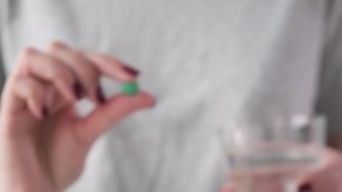 Yeşil baş ağrısı hapı ya da mavi arka planda bir bardak suyla ağrı kesici alan bir kadın. İlaç, sağlık, eczane ve tedavi konsepti almak. Seçici odak