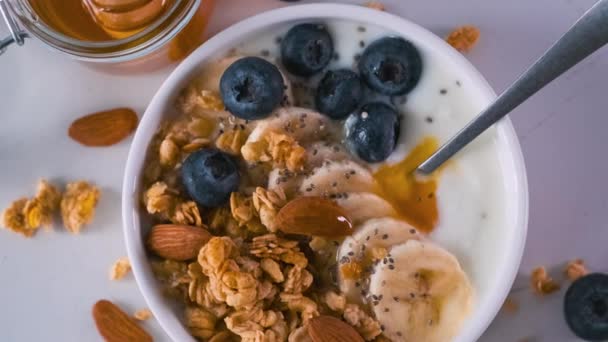 碗希腊酸奶与燕麦片 奇亚种子和蜂蜜在灰色的桌子上 带有复制空间的顶部视图 健康早餐 — 图库视频影像