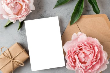 Pastel pembe şakayık çiçekli boş tebrik kartı ve gri arka planda hediye kutusu. Düğün davetiyesi. Model yap. Düz yatıyordu. Kadın Günü, Sevgililer Günü planı..