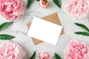 Beyaz mermer arka planda pembe şakayık çiçeklerinden yapılmış çerçevedeki boş tebrik kartı. Düğün davetiyesi. Model yap. Düz yatıyordu. Kadın Günü, Sevgililer Günü, Anneler Günü planı..