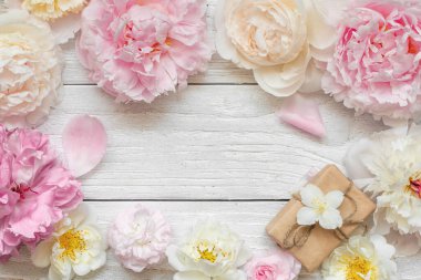 Çiçek kompozisyonu. Pembe şakayık, beyaz güller ve beyaz ahşap arka planda hediye kutusu olan yasemin çiçeklerinden yapılmış bir çerçeve. Düz yatıyordu. Üst Manzara. Kadınlar Günü, Düğün ya da kopyasıyla yıldönümü kartı