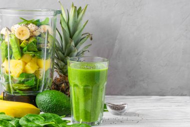 Sağlıklı detoks içeceği yapmak için taze meyve, ıspanak, avokado, chia tohumu ve blender ile bir bardak yeşil smoothie. Yemek pişirme konsepti
