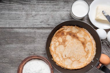 Kızartma tavasında krep pişirmek. Kırsal ahşap masadaki malzemelerle dolu tavada ince krepler. Kopyalama alanı olan üst görünüm. Nefis kahvaltı..