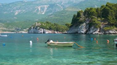 Budvanya Rivierası 'ndaki Adriyatik Denizi' nin turkuaz suyundaki tekne, Karadağ 'ın Sveti Stefan kenti. Yaz tatilinde. Popüler tatil köyü. Sakin sahne.