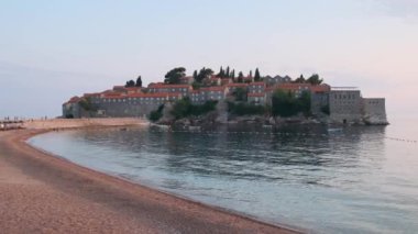 Karadağ 'ın Adriyatik Denizi' ndeki Budva Riviera 'da eski bir kasaba ve kumlu plajlı Sveti Stefan adası gün batımında. Popüler yaz tatili.