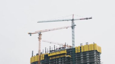 Gökdelenlerin çatısındaki inşaat alanında çalışan vinçler. Çok katlı evler, endüstriyel gelişmeler, inşaat şantiyesi mühendisliği. Zaman ayarlı. Yeni binaların konut sanayii.