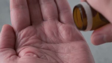 Erkek eline çeşitli haplar alan bir adam ilaç şişesinden tablet döküyor. İlaç, sağlık, eczane ve tedavi konsepti almak. Kapat.