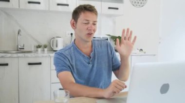 Mutlu Kafkasyalı adam dizüstü bilgisayarında video görüşmesi yapıyor. Evde otururken internetten selam veriyor. Erkek, arkadaşları ve ailesiyle görüntülü konuşma yapıyor. Uzaklık iletişimi kavramı.