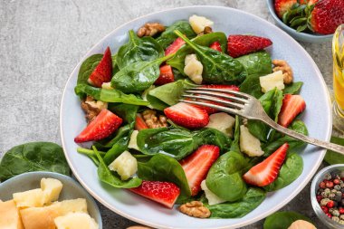 Ispanaklı yeşil salata, çilek, parmesan peyniri, ceviz ve çatallı zeytinyağı. Sağlıklı bir yaz vejetaryen yemeği..