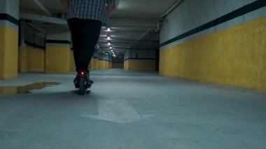 Artı yeraltı otoparkında e-scooter kullanan bir adam. Erkek, elektrikli scooter 'da bir arabanın yerine geçer. Elektrik ve ekolojik taşıma. Çevre dostu ulaşım. Sürdürülebilir yaşam tarzı kavramı.