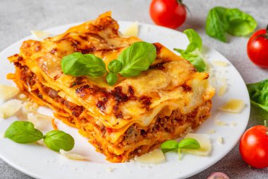 Taze fesleğenli lazanya, domates ve parmesan peynirini tabağa koy. İtalyan mutfağı. Akşam yemeği için lezzetli yemekler..