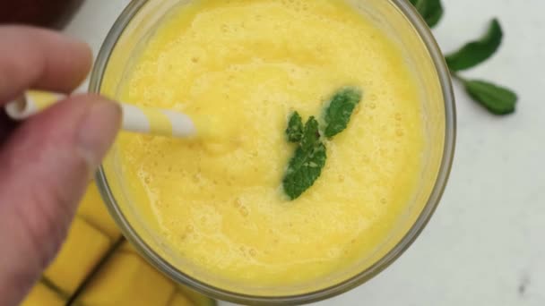 人的手把黄色的芒果 冰沙或奶昔和稻草混合在一起的倒影 顶部视图 热带健康饮料的概念 夏季饮料 — 图库视频影像