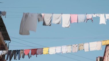 Binalar arasındaki çamaşır ipinde kurulanan temiz ve renkli giysiler. Şehirde ipte asılı temiz tekstil yıkadım. Çamaşır kurutuyorum..