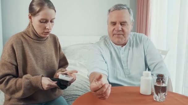 Gondoskodó Felnőtt Lánya Otthon Méri Vérnyomást Apjának Csuklóján Egy Fiatal — Stock videók