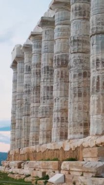 Güneş batarken, Attica, Yunanistan 'da Cape Sounion' daki Poseidon Tapınağı. Antik Yunan mimarisi. Yunan deniz tanrısının sütunlu tapınağının kalıntıları. Dikey oryantasyon. Seyahat ve turistik