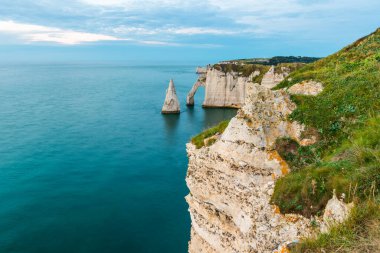 Beyaz tebeşir kayalıkları ve Etretat, Normandiya, Fransa 'nın doğal kemerleri. Normandie 'deki Atlantik kıyılarında gün batımında ünlü kaya oluşumları. Uzun pozlama. Seyahat ve turistik yerler.