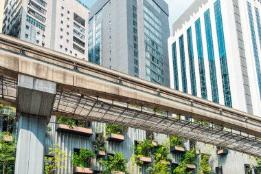 Modern gökdelenler ve Kuala Lumpur şehrinin dış cephesinde yeşil santralleri olan metro köprüsü, Malezya. Sürdürülebilir modern ve ekolojik mimari. Çevre dostu şehir ortamı.
