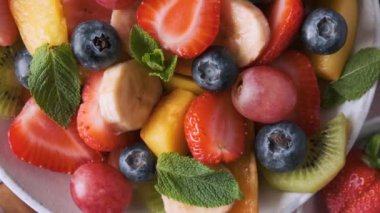 Pembe arka planda bir kasede sağlıklı taze meyve salatası. Üst Manzara. Kahvaltı için sağlıklı yaz yemekleri. Vejetaryen diyeti öğle yemeği için karışık tropikal meyve meyvesi. Kapat..