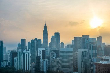 Kuala Lumpur şehrinin gökdelenleri ve yüksek binaları güneş doğarken, Malezya. Modern mimarisi olan Asya şehrinin şehir manzarası. Seyahat ve turizm geçmişi.