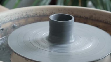 Ceramic cup on pottery wheel. Gray clay in workshop for creating a mug. Concept of creativity, handmade, hobby.