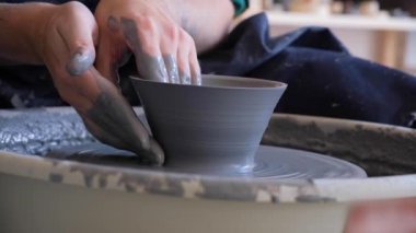 Erkek eller çanak çömlek üzerinde seramik kase yapıyor. Adam seramikçi atölyede gri kille çalışıyor ve bir kupa yaratıyor. Yaratıcılık kavramı, el yapımı, hobi.