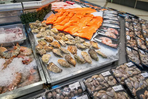 Çeşitli karidesler, somon filetosu, istiridye, midye, markette kabuklu deniz ürünleri. Süpermarkette buzlu buzdolabı rafında taze yiyecekler. Perakende arkaplan.