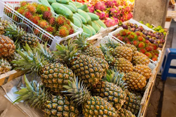 Markette çeşitli taze tropikal meyveler sergileniyor. Tayland, Phuket pazarında renkli ananas, rambutan, mango ve ejderha meyveleri sergileniyor..