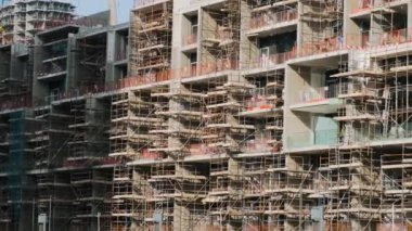 Dubai 'deki yapısal kalkınma sürecini vurgulayan, geniş yapı iskelesi ve iskelesi olan modern bina, BAE' de inşa ediliyor. İnşaat alanı. 