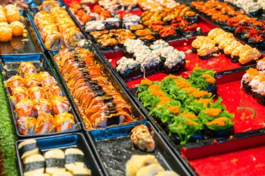 Tayland 'daki Phuket gece pazarındaki bir sokak gıda pazarında çeşitli suşi ruloları sergileniyor. Asya mutfağı ve aşçılık.