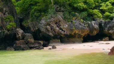 Phra Nang Mağarası, Railay Körfezi, Krabi, Tayland 'da gizli kumsalda yüzen bir adam. Turkuaz suyu, yeşil bitkileri ve kayaları olan gizli tropikal plajlar. Popüler turistik tatil