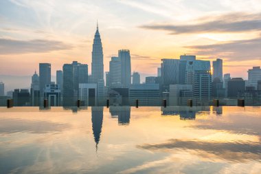 Kuala Lumpur şehri gökdelenlerin ve gökdelenlerin yansımalarıyla gün doğumunda Malezya 'nın sonsuz çatı havuzu. Modern Asya şehrinin şehir merkezi ve finans merkezi.
