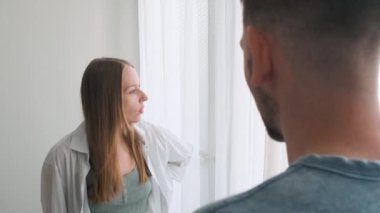 Kadın hararetli bir konuşmada erkekle tartışıyor, el hareketleriyle hayal kırıklığını dile getiriyor. Kızgın, endişeli, genç bir çift evde kavga ediyor ve tartışıyor. Sinirli bir eş sinirli bir şekilde bağırıyor ve bağırıyor.