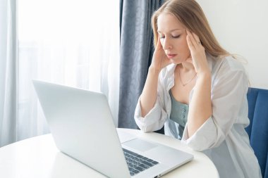Evde dizüstü bilgisayarla çalışan stresli iş kadını. Baş ağrısı, hayal kırıklığı, sıkılmış ve yorgun hissediyor. Uzak çalışma zorlukları olan bir kadın, tükenmişlik hissi, aşırı çalışma, uzun süreli duygusal ücret