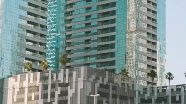 Dubai şehrinin çatılarında yansıtıcı cam cepheleri ve palmiye ağaçları olan modern yüksek binalar. Çatı bahçesi. Çevre dostu şehir ortamı. Sürdürülebilir modern ve ekolojik