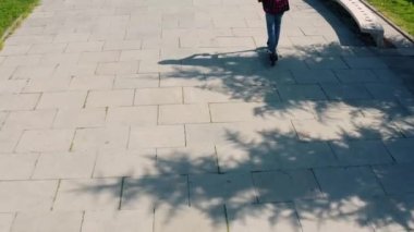 Güneşli yaz gününde şehir parkında elektrikli scooter kullanan bir turist. Erkek, açık havada e-scooter kullanıyor. İHA görüntüsü. Çevre dostu nakliye ve seyahat. Dikiz aynası. Sürdürülebilir yaşam tarzı kavramı.