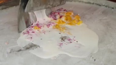 Sokak yemeklerinde soğuk bir tabakta karışık ejderha meyveleri ve mango ile rulo dondurma yapmak. Phuket, Tayland 'da, sokak yiyecek pazarında dondurmada kızartılmış dondurma pişirmek..