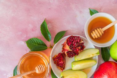 Rosh Hashana Yahudi Yeni Yıl yemeği, bal, nar ve pembe arka planda elmalar. Düz yat. Kopyalama alanı olan üst görünüm.