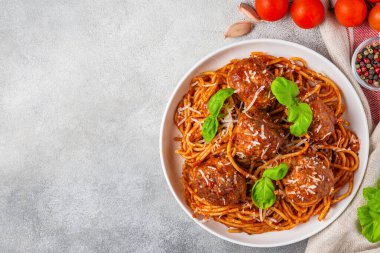 Domates soslu makarna soslu makarna, üzerinde parmesan peyniri ve gri beton arka planda taze fesleğen yaprakları. Lezzetli İtalyan yemekleri. Üst görünüm.