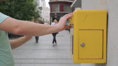 Erkek eli sarı bir posta kutusuna kartpostal atar. Turist adam kartpostal yolluyor ve sarı posta kutusuna koyuyor. Çapraz geçiş hobisi.
