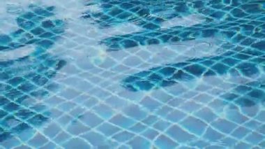 Yüzme havuzunda dalgalanmalar olan berrak mavi su yüzeyi soyut ışık yansımaları ve daireler oluşturur. Tayland 'daki Phi Phi adasında berrak mavi suyu olan tropik tatil köyü yüzme havuzu.