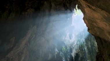 Batu mağarasının içinden akan güneş ışığı engebeli kaya oluşumlarını aydınlatıyor ve gizemli ve sakin bir atmosfer yaratıyor. Kuala Lumpur, Malezya. Hindu yolculuğu