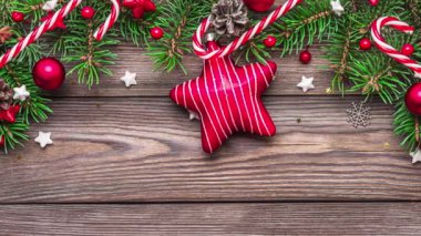 Köknar ağacı dalları, hediye kutuları, kırmızı yıldız ve süslemeler, kırsal ahşap masa üzerinde şeker ve çam kozalakları olan Noel arkaplanı. Düz yatıyordu. Mutlu yıllar ve kış tatili konsepti. Üst görünüm.