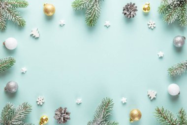 Noel kompozisyonu. Karlı köknar dallarından yapılmış çerçeve, dekorasyonlar, pastel mavi arka planda çam kozalakları. Düz yatıyordu. Mutlu yıllar ve kış tatilleri. Kopyalama alanı olan üst görünüm.