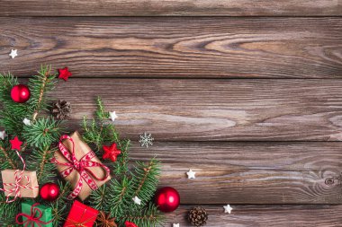 Köknar dalları, hediye kutuları, kırmızı süslemeler, sade ahşap masa üzerinde şeker ve çam kozalakları olan Noel arkaplanı. Düz yatıyordu. Mutlu yıllar ve kış tatilleri. Kopyalama alanı olan üst görünüm.
