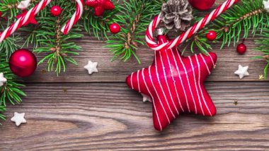 Köknar ağacı dalları, hediye kutuları, kırmızı yıldız ve süslemeler, kırsal ahşap masa üzerinde şeker ve çam kozalakları olan Noel arkaplanı. Düz yatıyordu. Mutlu yıllar ve kış tatili konsepti. Üst görünüm.