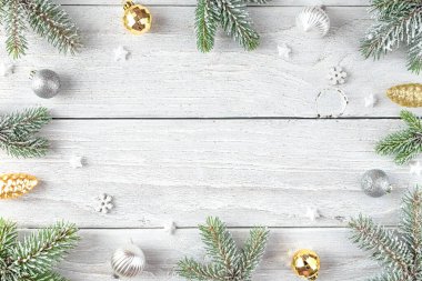 Karlı köknar dallarından yapılmış Noel çerçevesi, altın süslemeler, beyaz ahşap arka planda çam kozalakları. Düz yatıyordu. Mutlu yıllar ve kış tatilleri. Kopyalama alanı olan üst görünüm.
