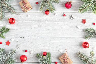 Karlı köknar dallarından, hediye kutularından, kırmızı süslemelerden ve beyaz ahşap arka planda çam kozalaklarından yapılmış Noel çerçevesi. Düz yatıyordu. Mutlu yıllar ve kış tatilleri. Kopyalama alanı olan üst görünüm.