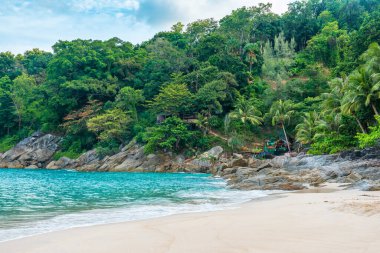 Tayland 'da Phuket Adası' nda kimsesiz özgürlük plajı. Kristal berrak suları, kumlu kıyıları, palmiye ağaçları ve parlak mavi gökyüzünün altında yeşil yaprakları olan tropik bir sahil. Popüler yaz ve kış tatili