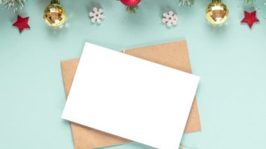 Noel tebrik kartı ve içinde karlı köknar ağacı dalları, hediye kutuları, süslemeler ve pastel mavi arka planda çam kozalakları olan bir zarf. Düz yatıyordu. Model yap. Mutlu yıllar ve kış tatilleri daveti