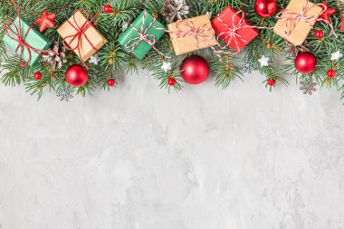 Noel arkaplanı köknar ağacı dalları, hediye kutuları, kırmızı süslemeler ve gri beton masa üzerinde çam kozalakları. Düz yatıyordu. Mutlu yıllar ve kış tatilleri planı. Kopyalama alanı olan üst görünüm.